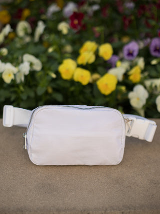 a white sling bag with zip closure and three pockets for your necessities