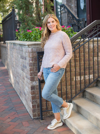 a pale pink cable stitch sweater in a relaxed fit perfect for cozy fall fashion shown with denim pants