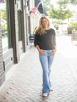 a chic sweater in black with long sleeves and a relaxed fit perfect for layering in every season shown with denim pants