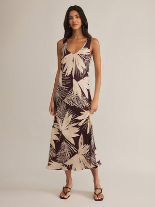 a breezy loose fit satin v neck maxi dress with a brown and cream lava rock pattern worn with brown sandals