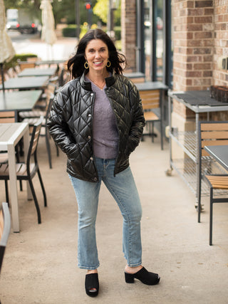 a black faux leather puffer jacket with quilted textures and a cool pop collar great for winter fashion shown with denim