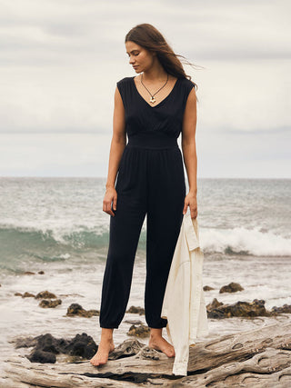 black one piece summer jumpsuit with v-neck keyhole details and smocked waist with white jacket