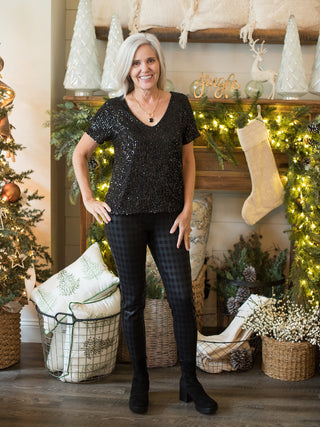 wear this flattering black sequined short sleeve top for a glamorous vibe at holiday parties with plaid pants