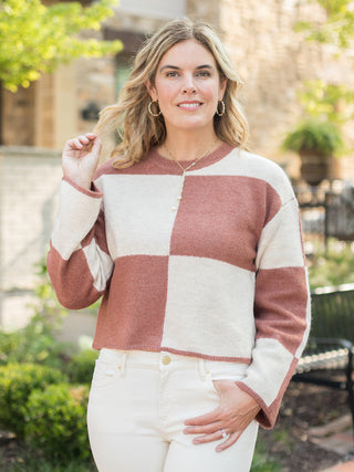 a chunky fall sweater with rust and white color block squares that crops at the waist with long sleeves 