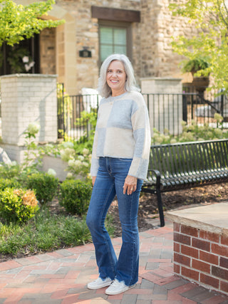 a chunky fall sweater with pale blue and cream color block squares that crops at the waist shown with denim pants