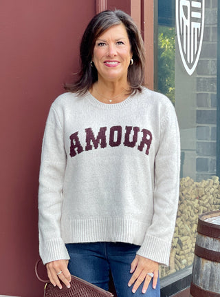 a light gray crew neck sweater with amour written in dark red letters perfect for comfortable and casual dressing