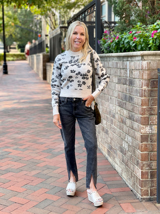 a pale brown sweater with black flower pattern and a mock turtleneck shown with split hem pants
