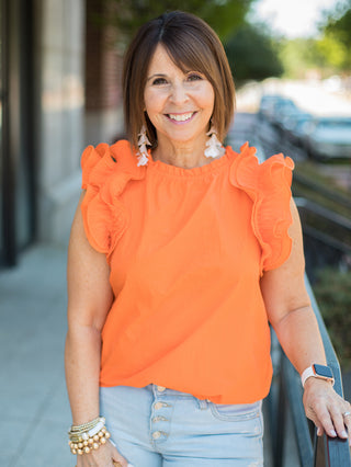 an orange ruffled sleeveless top with pleated crepe sleeves and a ruffled round neckline