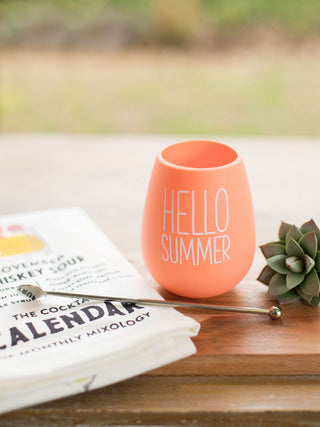 a bright orange silicone wine tumbler that is reusable and shatterproof reads hello summer