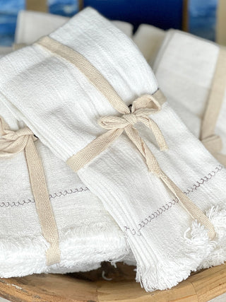 natural ivory white square napkins made of 100% cotton with delicate embroidery and fringe edge detail tied with ribbon