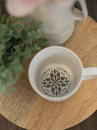 a hand painted mandala design on the inside bottom of the white coffee mug