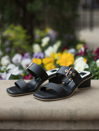 Slip on black leather block heel sandal with wide buckled straps gold grommet detail and square toe