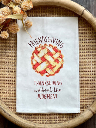 a white tea towel that reads friendsgiving thanksgiving without the judgement perfect for thanksgiving fall decor gifts
