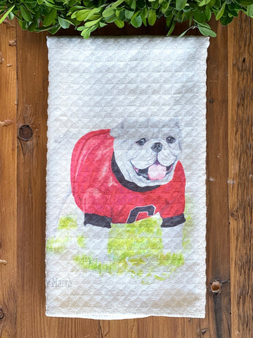 a cream tea towel featuring a watercolor uga bulldog atop a waffle weave fabrication