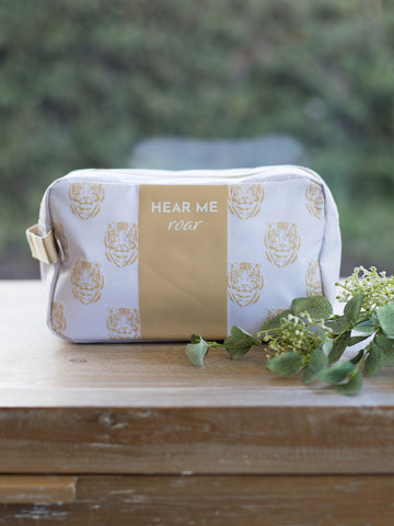 this white cosmetic bag has a gold tiger face pattern and hear me roar written across the front