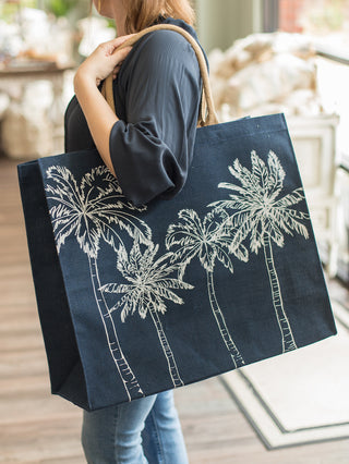 a dark blue jute tote with delicate palm trees and a small inside pocket to keep your essentials safe