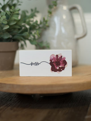 a white wooden block art display with watercolor flowers that reads mom