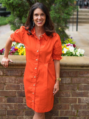a button up orange dress in a relaxed silhouette with an above knee cut and short sleeves with shirred cuffs
