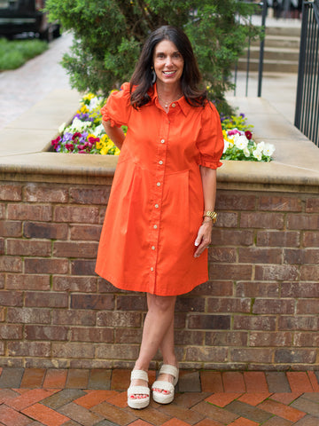 a button up orange dress in a relaxed fit with an above knee cut and short shirred sleeves shown with white sandals