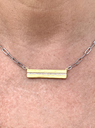 gold bar necklace with row of dainty rhinestones and silver paperclip chain close up
