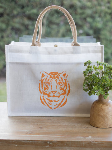 an easy tiger jute tote bag with a front pocket featuring an orange tiger face on a white background