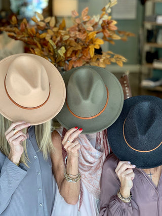 an olive green wide brimmed hat with a tan faux leather band across the top shown with charcoal and beige varieties 